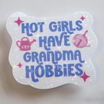 Transparent sticker with text 'Hot girls have grandma hobbies' on a light gray background