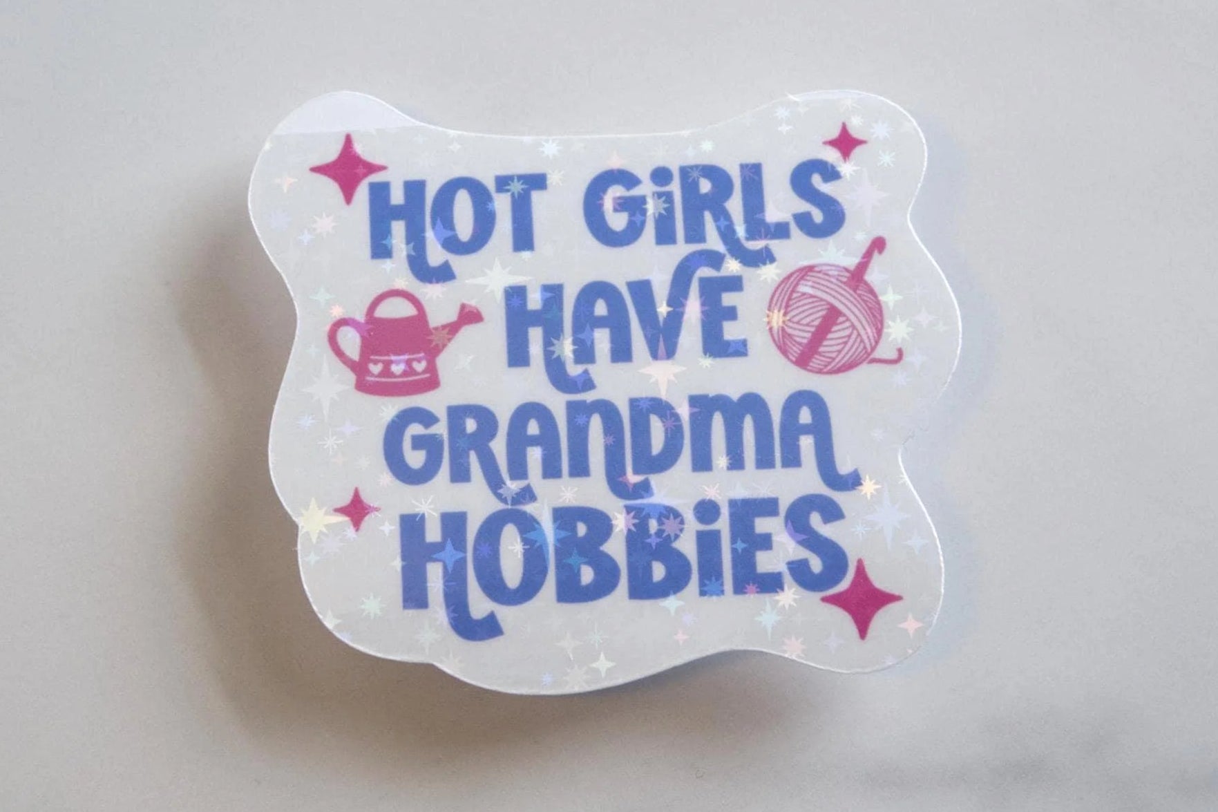Transparent sticker with text 'Hot girls have grandma hobbies' on a light gray background