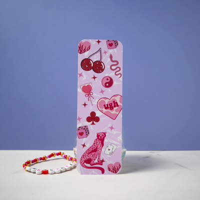 Feral in Pink double-sided matte bookmark by Ink & Static, featuring cherries, dice, a pink cheetah, yin yang, and heart graphics on a pink background