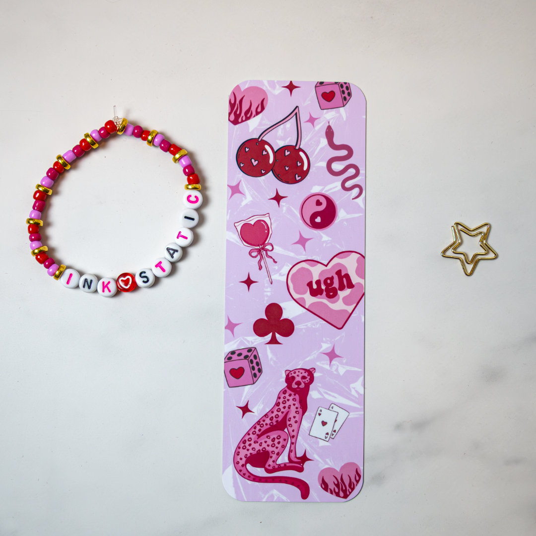 Feral in Pink double-sided matte bookmark by Ink & Static, featuring cherries, dice, a pink cheetah, yin yang, and heart graphics on a pink background