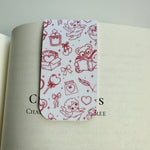 white magnetic bookmark with red doodles on a book page
