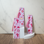 3 bookmarks with pink tassel on a white pedestal against a marble background