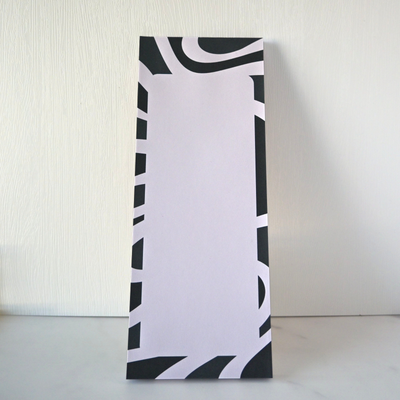 Black and white patterned fridge notepad on a light gray surface with a neutral background