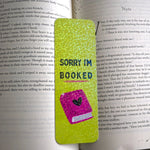 Green bookmark with 'Sorry I'm Booked' text on a book page