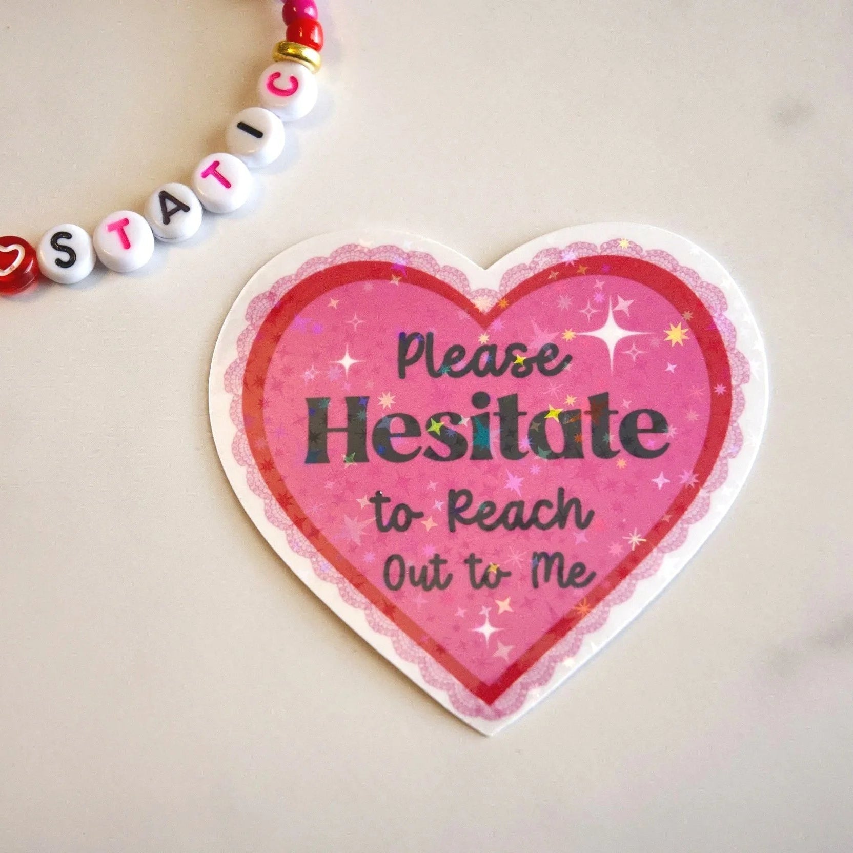 Heart-shaped sign with 'Please Hesitate to Reach Out to Me' text on a light background