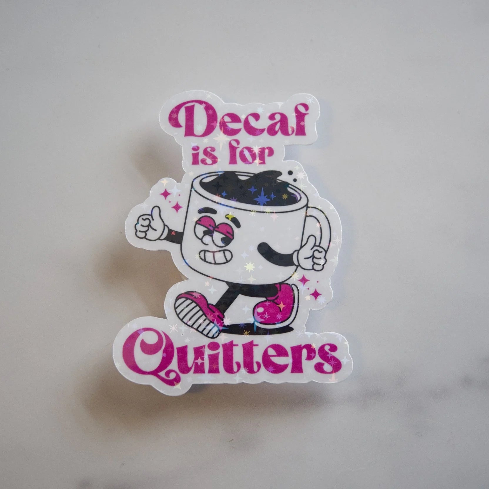 Sticker with cartoon coffee cup character and text 'Decaf is for Quitters' on a light gray background