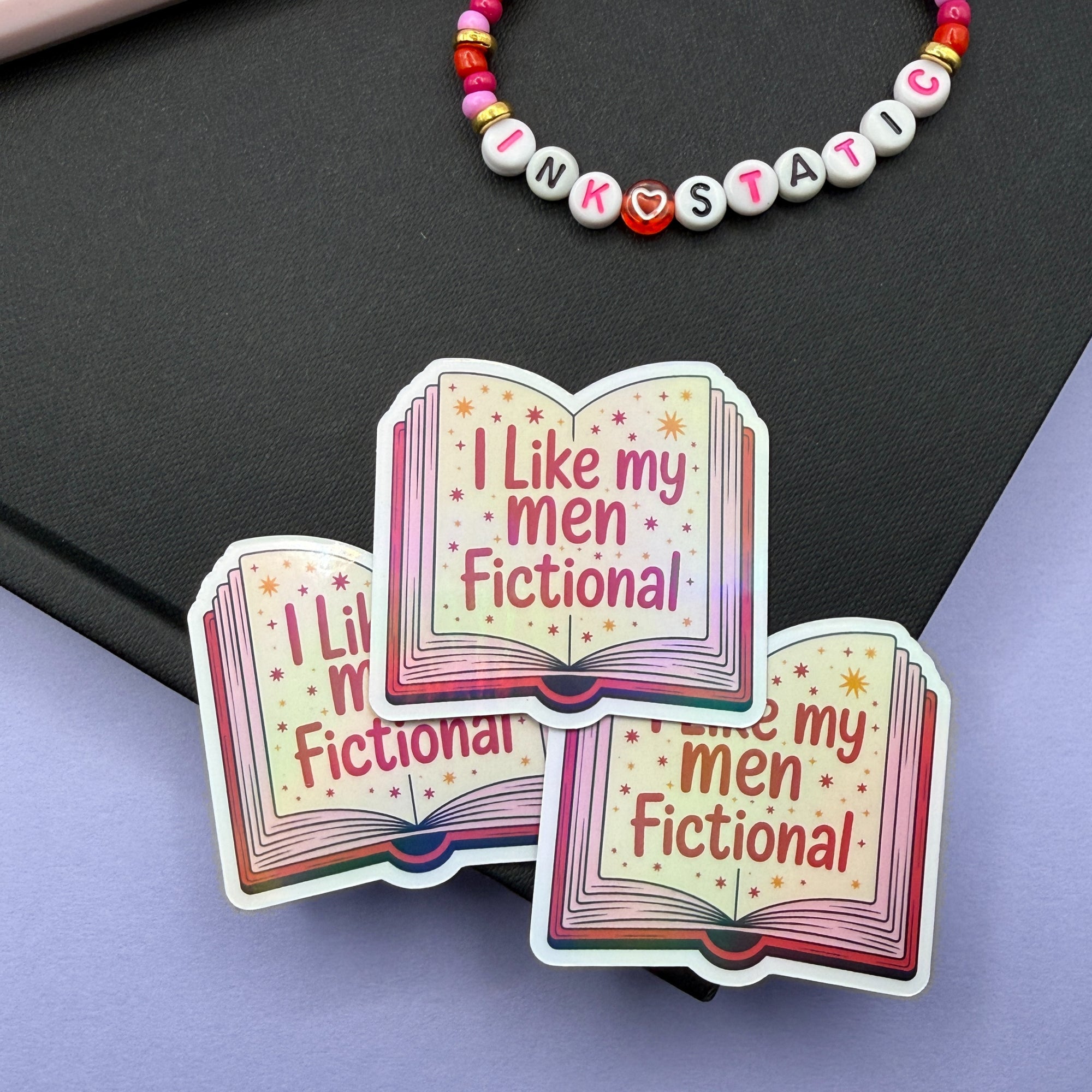 Colorful book-shaped sticker with text 'I Like my men Fictional' on a black and purple background.