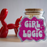 Glass jar with cork lid and 'Girl Logic' label, red balloon animal in the background