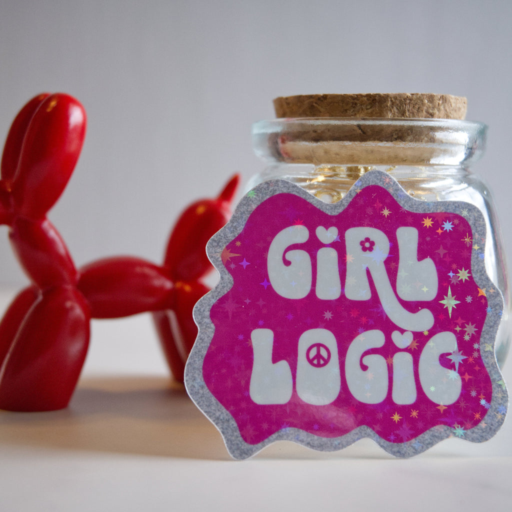 Glass jar with cork lid and 'Girl Logic' label, red balloon animal in the background