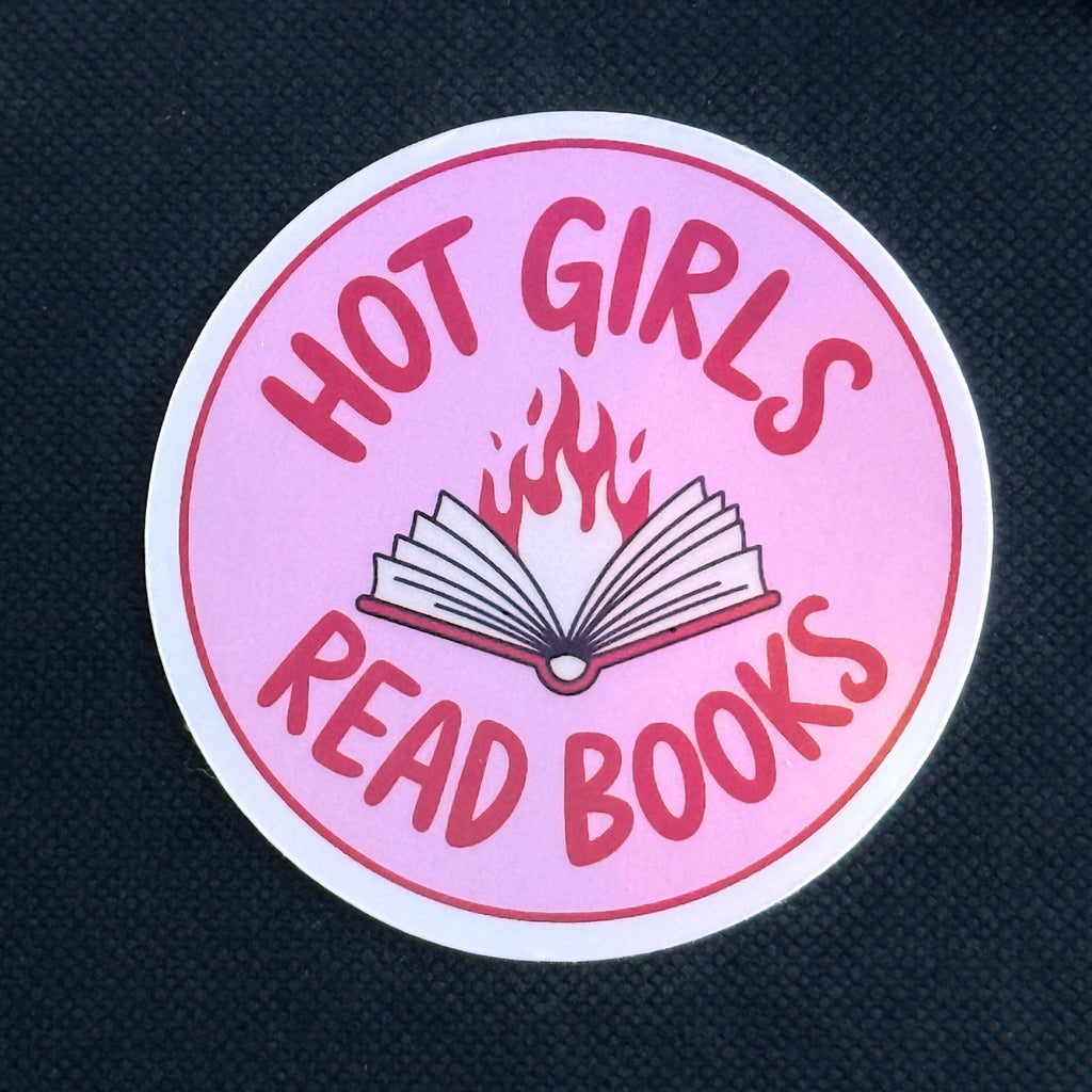 Pink round sticker with text 'Hot girls read books' on a dark background