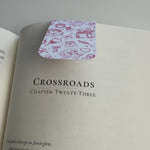 white magnetic bookmark with red hand drawn doodles snapping over book page
