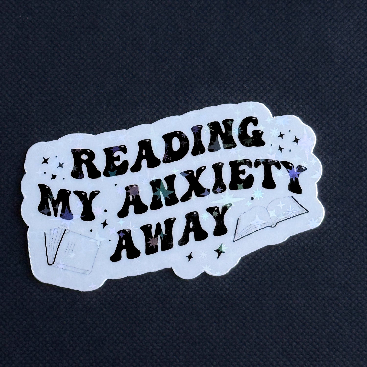 Sticker with 'Reading my anxiety away' text on a dark background