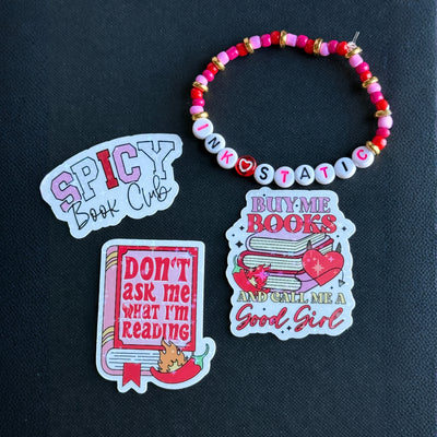 Set of book-themed stickers and a beaded bracelet on a dark background