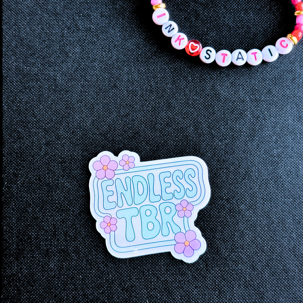 Sticker with 'Endless TBR' text on a dark fabric background