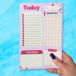 Notepad with daily schedule sections held by a hand on a blue background