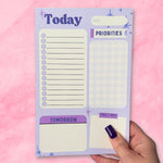 Notepad with daily schedule layout on a pink background