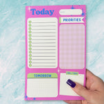 Pink notepad with various sections on a light blue textured background