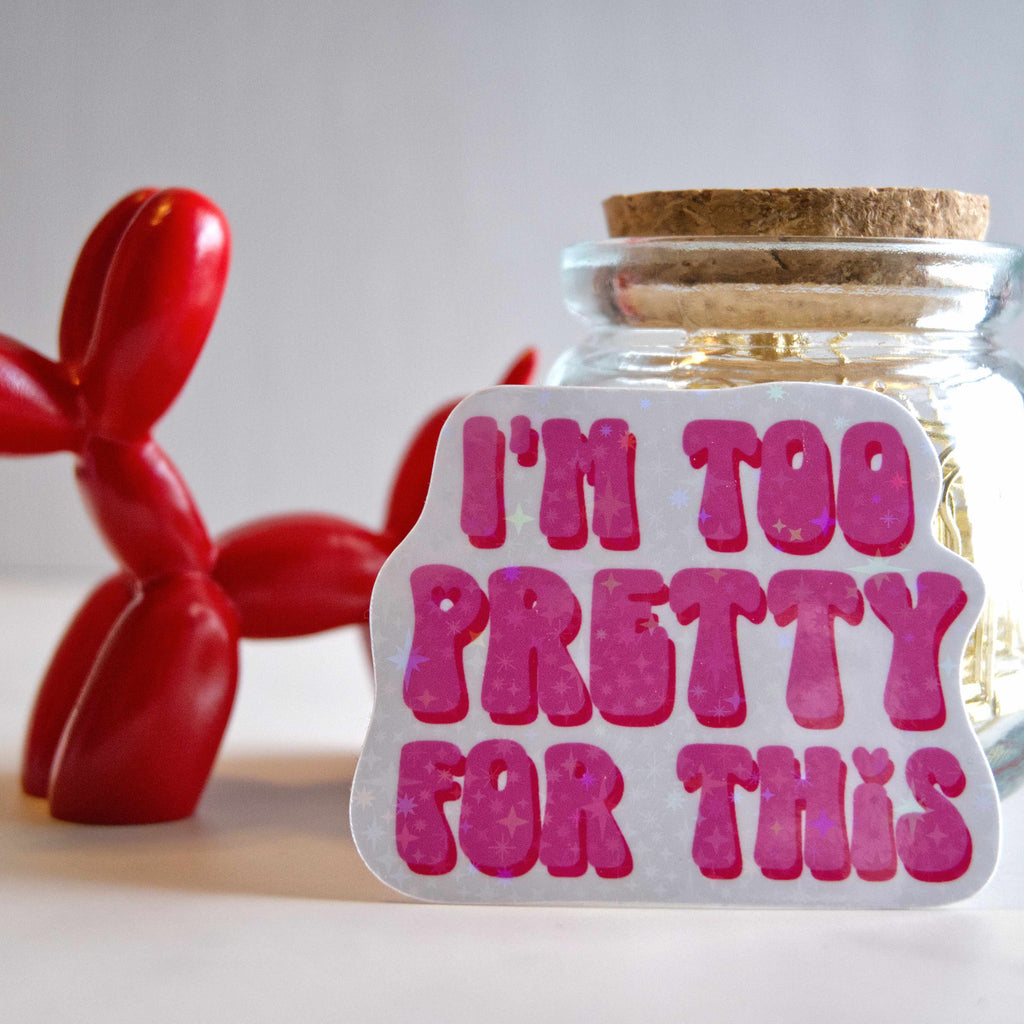 Glass jar with cork lid and 'I'm too pretty for this' sticker, next to a red balloon dog on a light background